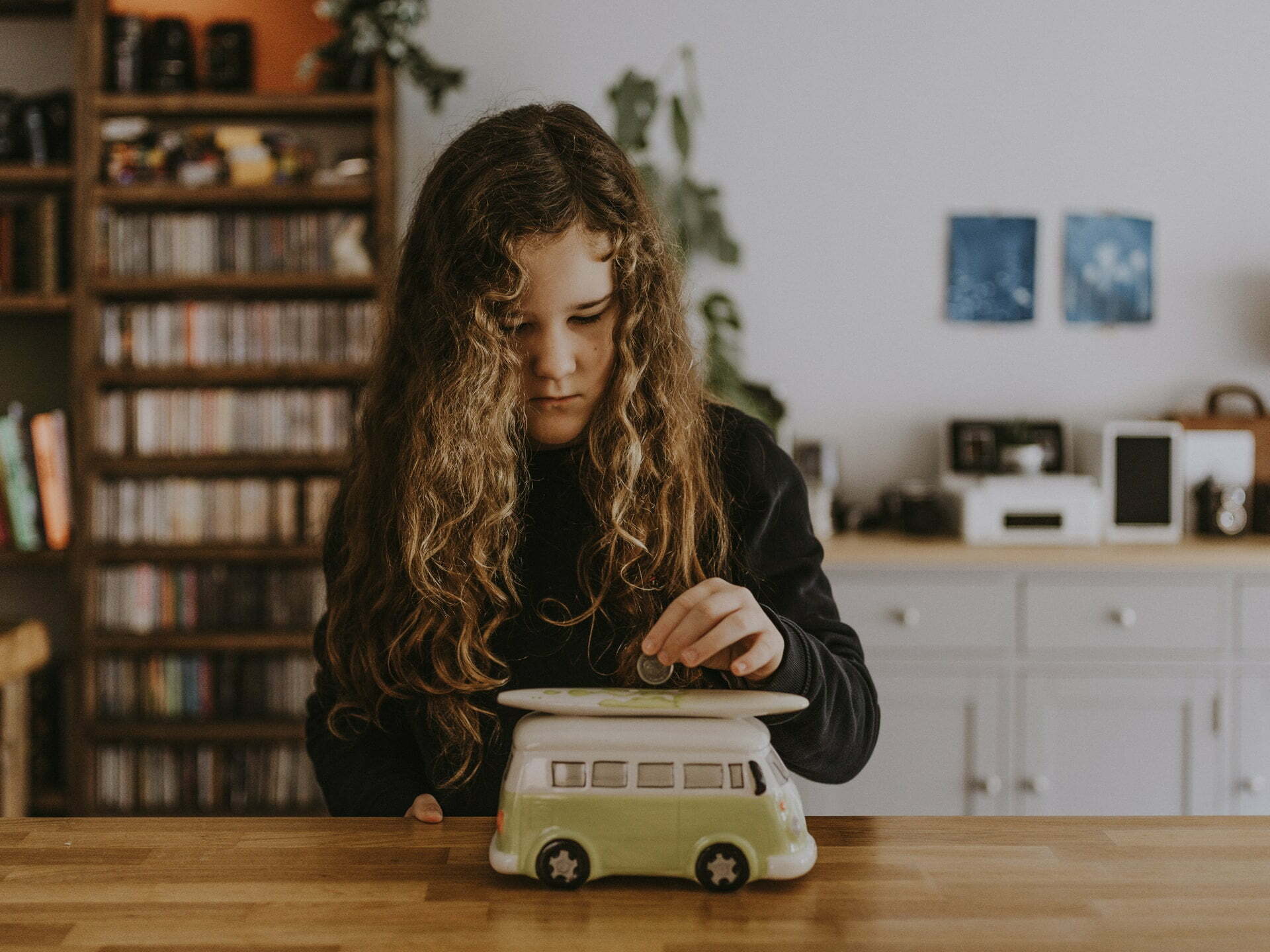 a person with long hair sitting at a desk with a toy car