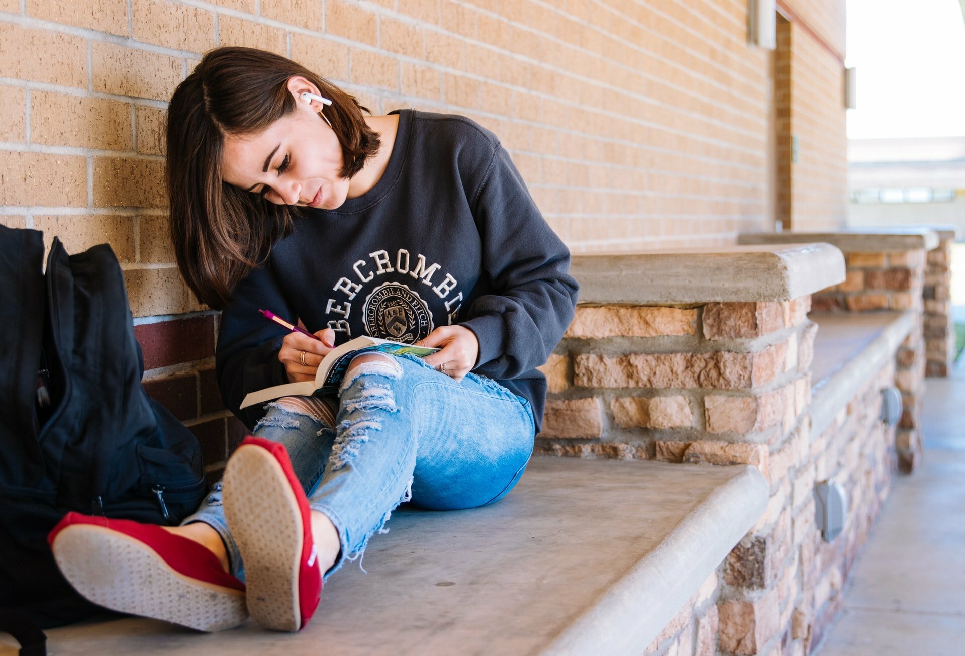 a woman sitting on a bench with a man reading a book