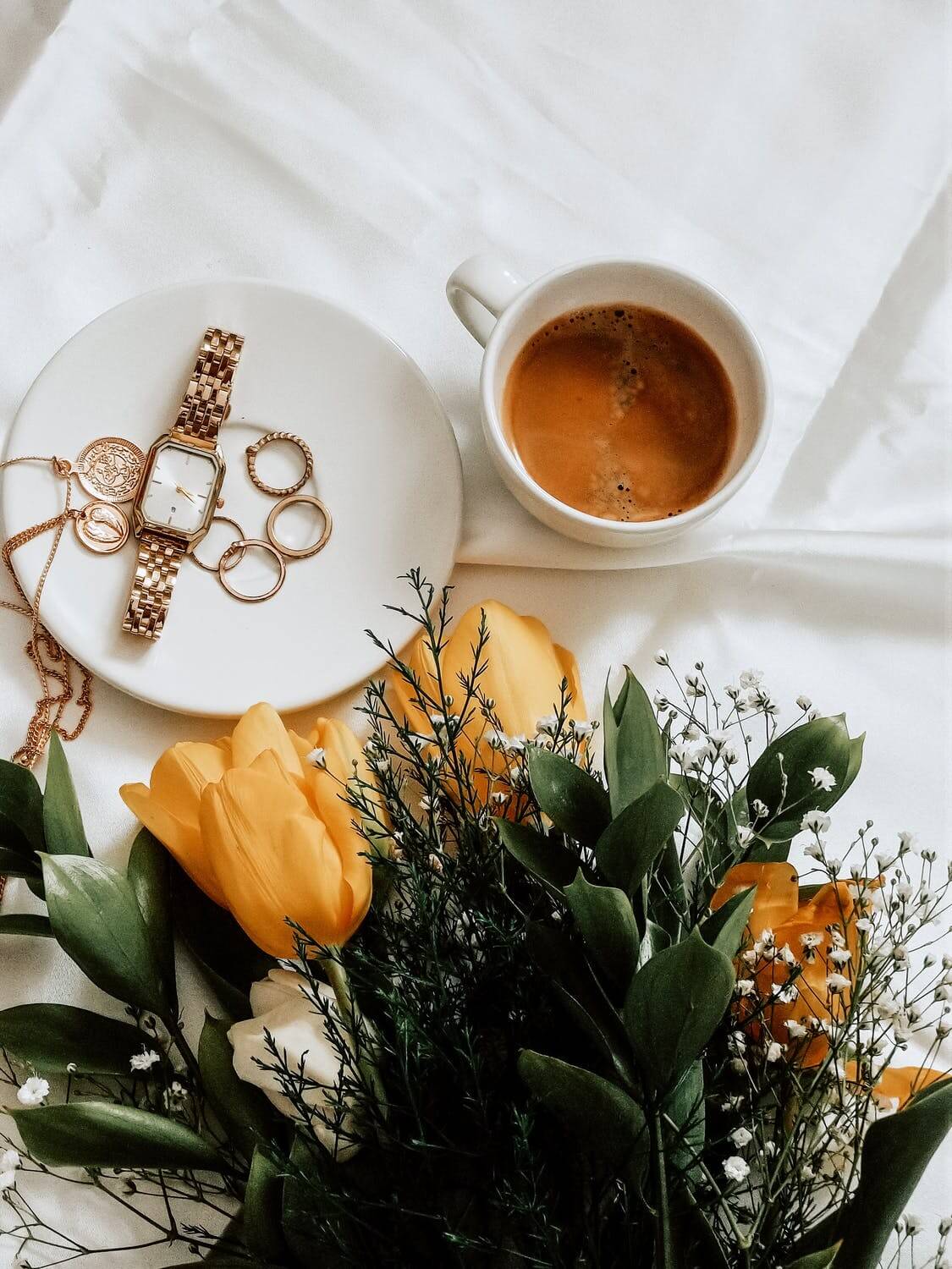 a cup of tea next to a plate of roses and a candle