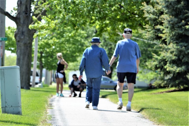 Active senior citizens holding hands and walking for exercise